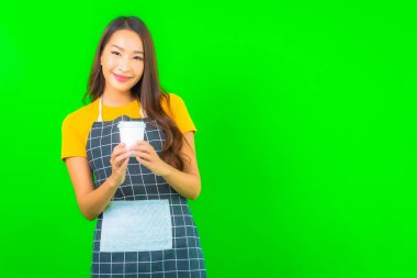 Güzel bir Asyalı kadın portresi yeşil izole edilmiş arka planda önlük giyiyor.