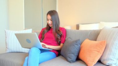 Evde dizüstü bilgisayarla çalışan Asyalı güzel bir kadının görüntüleri.