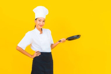 Sarı izole arka planda siyah şapkalı güzel Asyalı şef kadın portresi.