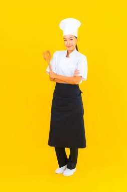 Sarı izole arkaplanda spatulası olan güzel, genç Asyalı şef kadın portresi.