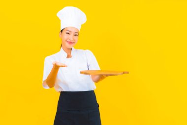 Sarı izole arka planda tahta kesim tahtasıyla güzel bir Asyalı kadın portresi.