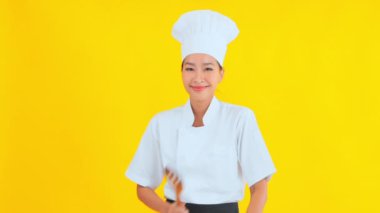 Asyalı güzel aşçının portresi. Sarı arka planda ahşap bir spatulası var.