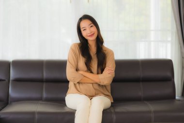 Güzel bir Asyalı kadın portresi. Mutlu bir gülümseme. Oturma odasındaki kanepede rahatla.