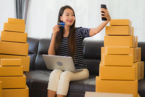 Portrait beautiful young asian woman with container cardboard parcel box packaging prepare for shipping for customer online shopping in living room