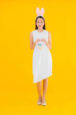 Sarı izole edilmiş arka planda paskalya yumurtası olan güzel Asyalı kadın portresi.