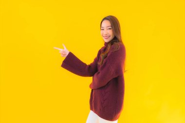 Güzel Asyalı kadın gülümsüyor. Sarı izole edilmiş arka planda başka bir eylemde mutlu.