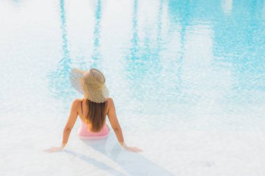 Güzel bir Asyalı kadın portresi. Tatil gezisinde deniz manzaralı açık havuz etrafında rahatça yüzebiliyor.