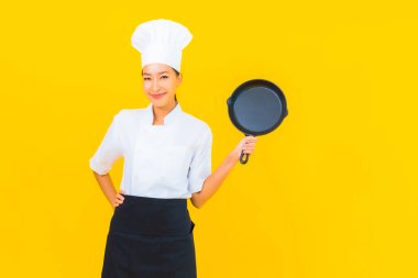 Sarı izole arka planda siyah şapkalı güzel Asyalı şef kadın portresi.