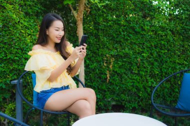 Genç Asyalı kadın açık hava manzarası için akıllı cep telefonu kullanıyor.