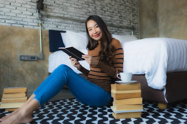 Genç Asyalı Kadın Elinde Kahve Fincanıyla Yatak Odasında Kitap Okuyor — Stok fotoğraf