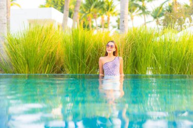 Güzel bir Asyalı kadın portresi. Rahatlayın, gülümseyin. Tatil için oteldeki yüzme havuzunun keyfini çıkarın.