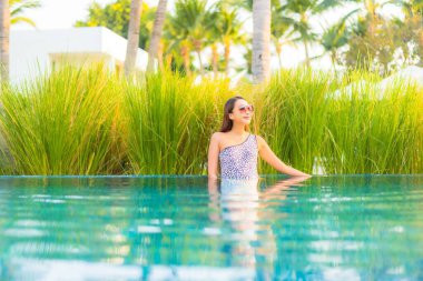 Güzel bir Asyalı kadın portresi. Rahatlayın, gülümseyin. Tatil için oteldeki yüzme havuzunun keyfini çıkarın.