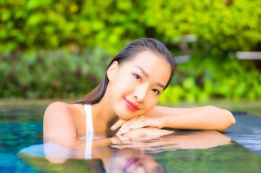 Güzel bir Asyalı kadın portresi. Rahatlayın, gülümseyin. Tatil için oteldeki yüzme havuzunun keyfini çıkarın.