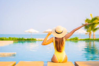 Güzel bir Asyalı kadın portresi. Rahatlayın, gülümseyin. Tatil için oteldeki yüzme havuzunun keyfini çıkarın.