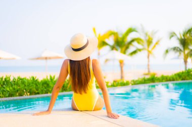 Güzel bir Asyalı kadın portresi. Rahatlayın, gülümseyin. Tatil için oteldeki yüzme havuzunun keyfini çıkarın.