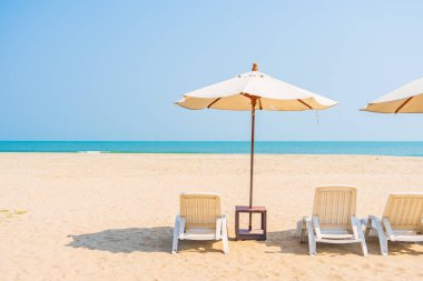 Şemsiye ve sandalye deniz kıyısında gezmek için mavi gökyüzünde