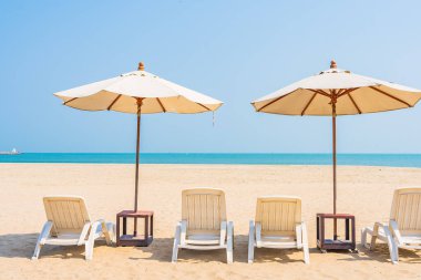 Şemsiye ve sandalye deniz kıyısında gezmek için mavi gökyüzünde