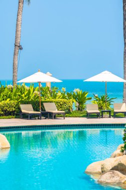 Açık yüzme havuzu, deniz kıyısı, şemsiye ve tatil için sandalye.