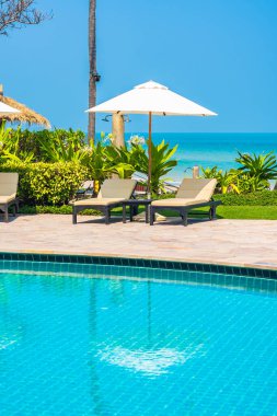 Açık yüzme havuzu, deniz kıyısı, şemsiye ve tatil için sandalye.