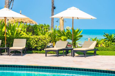 Açık yüzme havuzu, deniz kıyısı, şemsiye ve tatil için sandalye.