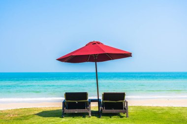 Boş güverte sandalyesi şemsiyesi ile sahil kıyısı okyanus mavi gökyüzü tatil için