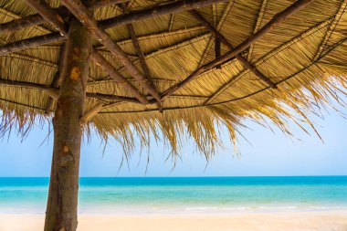 Boş güverte sandalyesi şemsiyesi ile sahil kıyısı okyanus mavi gökyüzü tatil için