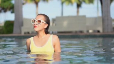 Güzel bir Asyalı kadın portresi otel havuzunda rahatça yüzebiliyor.