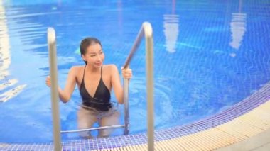Güzel bir Asyalı kadın portresi otel havuzunda rahatça yüzebiliyor.