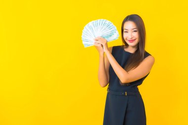 Güzel Asyalı iş kadını portresi. Sarı arka planda bir sürü parası ve parası var.