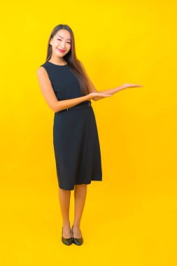 Güzel Asyalı iş kadını portresi. Sarı arka planda hareketli bir gülümseme.