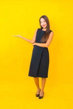 Güzel Asyalı iş kadını portresi. Sarı arka planda hareketli bir gülümseme.