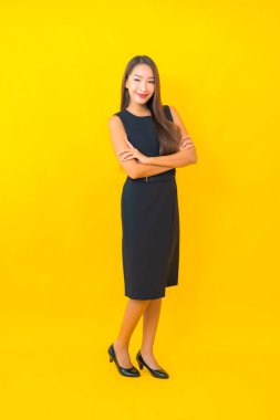 Güzel Asyalı iş kadını portresi. Sarı arka planda hareketli bir gülümseme.