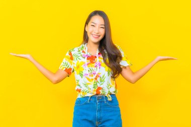 Güzel bir Asyalı kadın Tayland 'daki sonkran festivali için sarı arka planda renkli bir gömlek giyiyor.