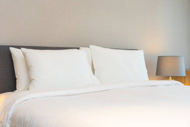 Yatak odasının iç dekorasyonuna beyaz yastık ve battaniye. İçinde lamba var.