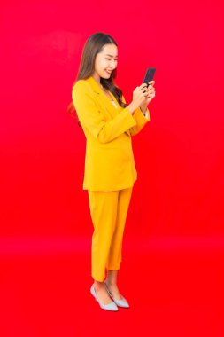 Portre güzel genç iş kadını Asyalı kırmızı arka planda akıllı cep telefonu kullanıyor