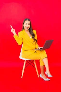 Portre güzel genç iş kadını Asyalı kadın kırmızı arka planda bilgisayar bilgisayarı kullanıyor