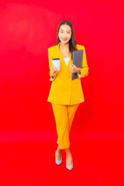 Kırmızı arka planda kahve fincanı olan Asyalı güzel bir iş kadını portresi.