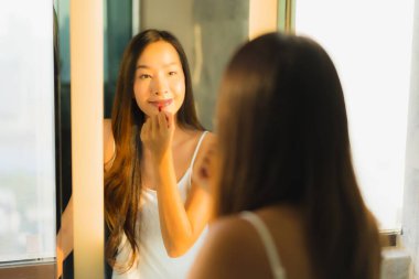 Güzel bir Asyalı kadın portresi makyaj malzemesi makyaj malzemesi ve yüz makyajı ile banyo içinde yüz maskesi.