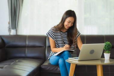 Coronaviruse ya da covid19 'dan korunmak için kanepeye dizüstü bilgisayar defteri ya da bilgisayar kullanan güzel Asyalı kadın portresi