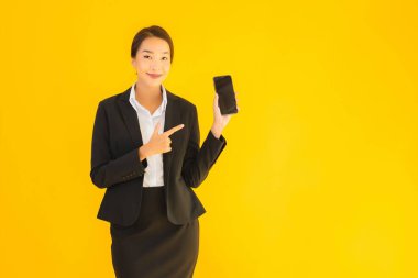Portre güzel genç Asyalı kadın akıllı cep telefonu ve kahve fincanı ile izole edilmiş sarı arka planda