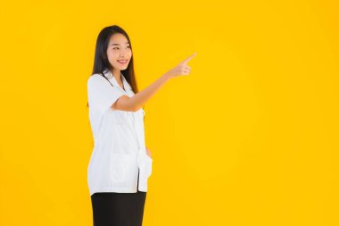 Güzel bir portre genç Asyalı kadın gülümsüyor. Hastane ve klinikte çalışmanın mutluluğu sarı izole edilmiş arka planda.