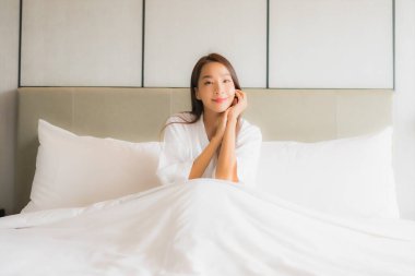Güzel bir Asyalı kadın portresi. Yatak odasının içinde mutlu bir gülümseme.