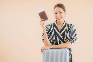 Çantalı güzel bir Asyalı kadın. Pasaportu ve uçak bileti kahverengi arka planda.