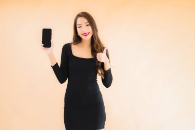 Güzel Asyalı genç bir kadının portresi mutlu bir şekilde gülümsüyor renkli arka planda akıllı cep telefonu kullan