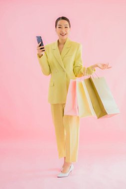 Renkli arka planda alışveriş çantası taşıyan güzel Asyalı iş kadını portresi.