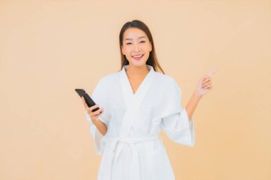 Güzel bir Asyalı kadın portresi izole edilmiş arka planda akıllı cep telefonu kullanır.