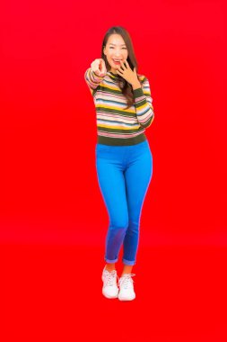 Güzel bir Asyalı kadının portresi. Kırmızı izole edilmiş arka planda hareketli gülümsüyor.