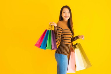 Güzel, genç Asyalı bir kadının portresi. Mutlu bir gülümseme. Alışveriş çantasının rengi sarı izole arka planda.