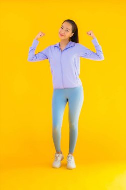 Sarı izole edilmiş arka planda spor giysili güzel Asyalı kadın portresi egzersize hazır.