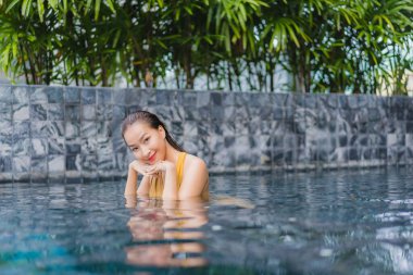 Güzel bir Asyalı kadın portresi otel havuzunda rahatça yüzebiliyor.
